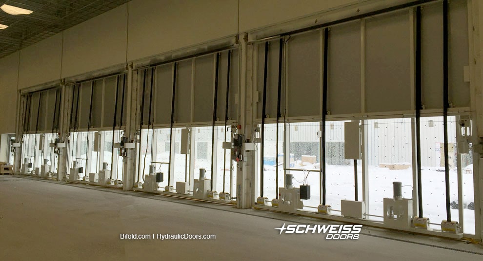 Schweiss Liftstrap doors equipped with automatic latches, emergency back-ups, remotes, weatherproof electrical and door base safety edges.
